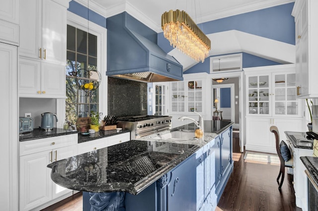 kitchen featuring pendant lighting, high end stove, a center island with sink, and custom exhaust hood