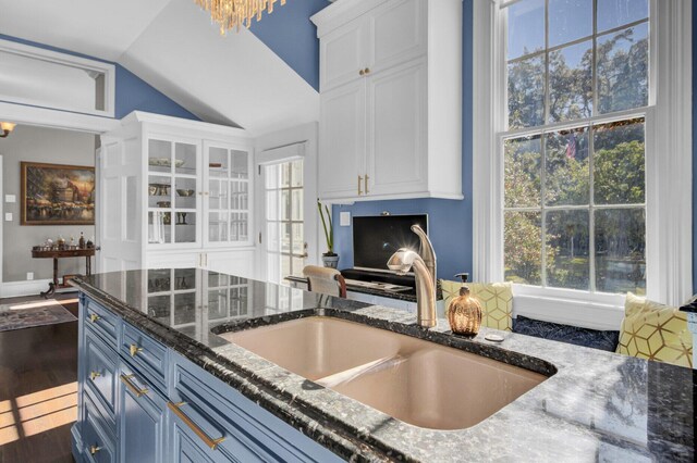 kitchen with lofted ceiling, white cabinetry, dark wood-type flooring, and sink