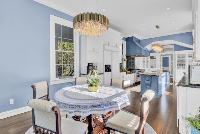 dining area with crown molding, sink, dark wood-type flooring, and a notable chandelier