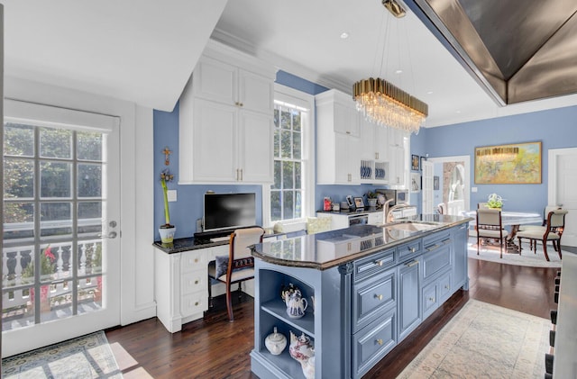 kitchen featuring white cabinets, a center island with sink, blue cabinets, and dark wood-type flooring