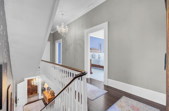 stairway with a chandelier, wood-type flooring, and ornamental molding