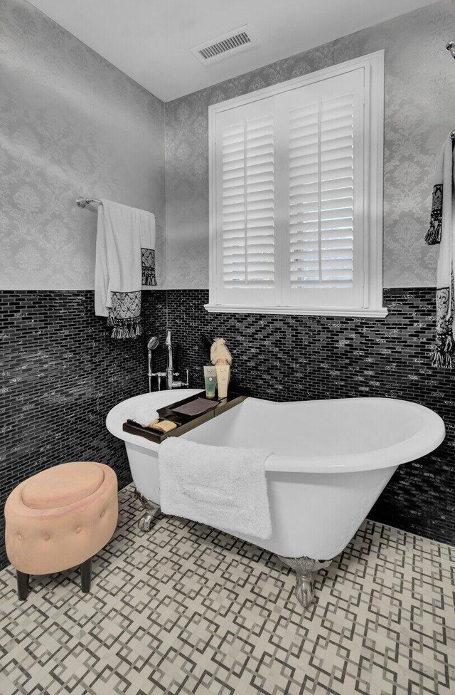 bathroom with a washtub and tile walls