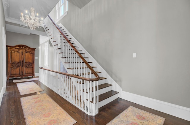 staircase featuring hardwood / wood-style flooring and an inviting chandelier