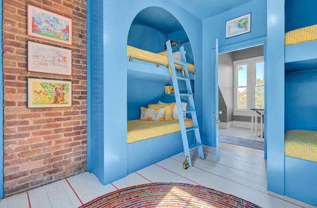 bedroom with wood-type flooring and brick wall