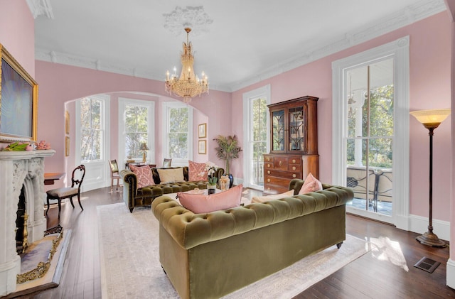 living room with hardwood / wood-style floors, an inviting chandelier, a wealth of natural light, and crown molding