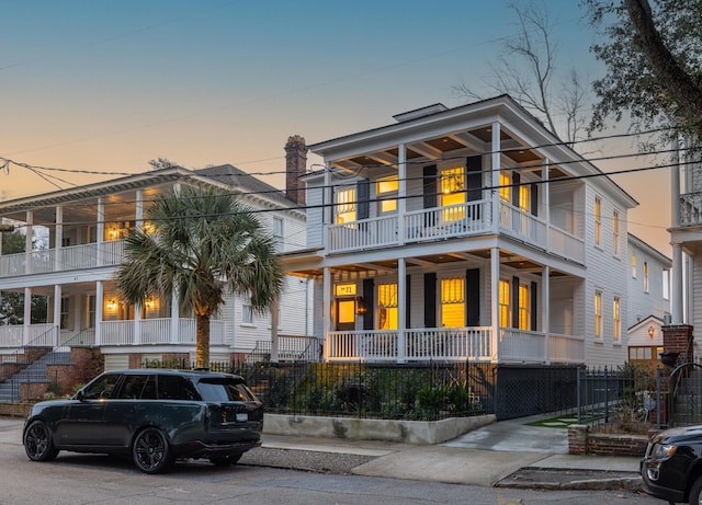 view of front of property featuring covered porch, fence, and a balcony