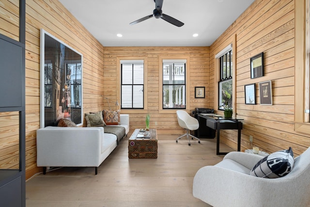 sitting room with a ceiling fan, recessed lighting, wooden walls, and wood finished floors