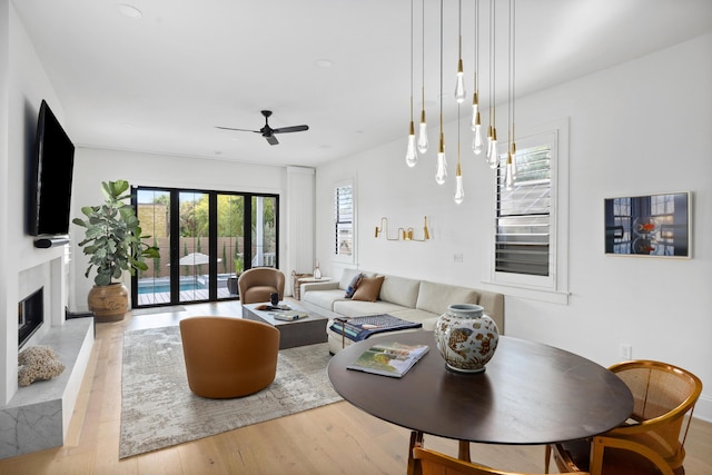 living area featuring a ceiling fan, french doors, a fireplace, and wood finished floors