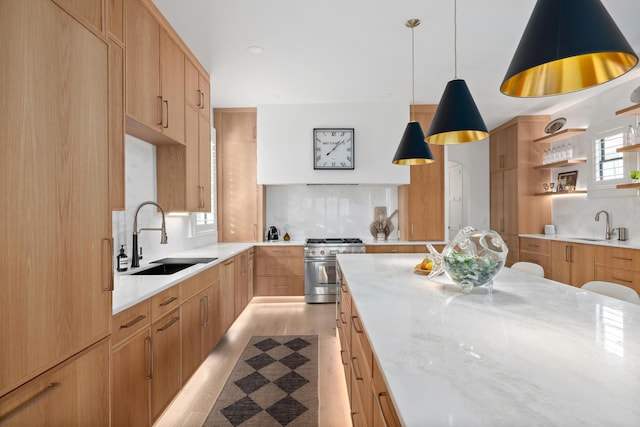 kitchen featuring tasteful backsplash, high end stove, a sink, and light stone counters