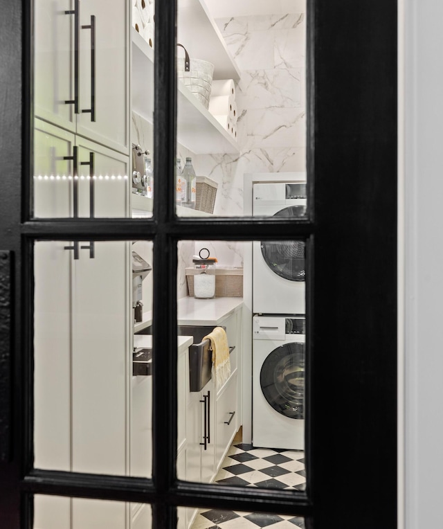 washroom with stacked washer and clothes dryer and cabinet space