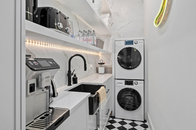 washroom featuring laundry area, a sink, stacked washing maching and dryer, and tile patterned floors