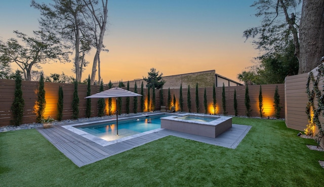 view of swimming pool with a fenced backyard, a pool with connected hot tub, and a lawn