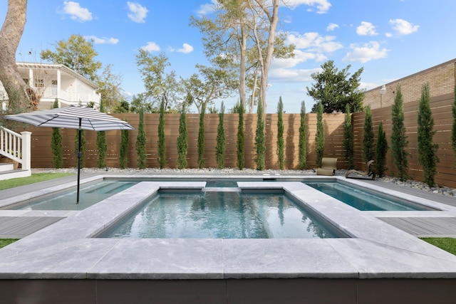 view of pool with a fenced backyard and a pool with connected hot tub