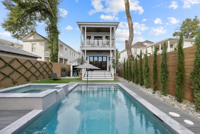 rear view of house with a balcony, a fenced backyard, a pool with connected hot tub, and a ceiling fan