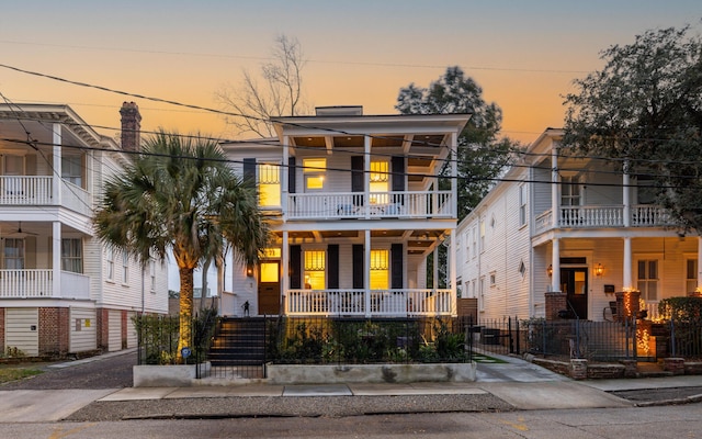 view of front of house featuring a balcony, covered porch, and a fenced front yard