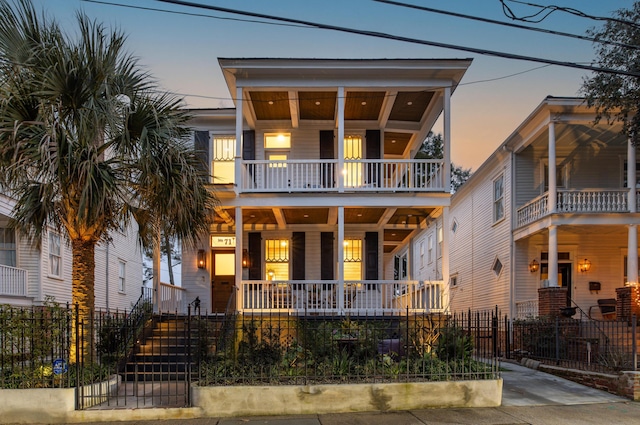 view of front of house with covered porch, a fenced front yard, and a balcony