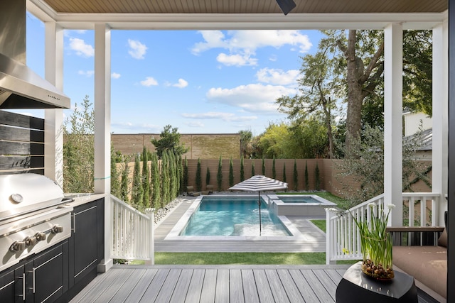 wooden deck with an outdoor kitchen, area for grilling, a fenced backyard, and a pool with connected hot tub