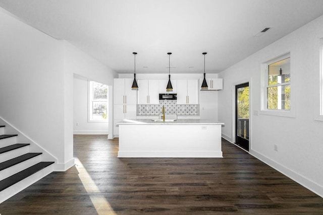 kitchen featuring tasteful backsplash, black microwave, dark wood-style floors, white cabinetry, and a sink