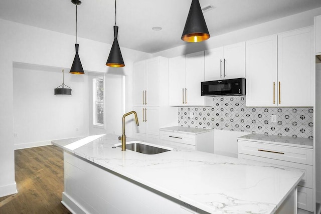 kitchen with a sink, visible vents, light stone countertops, and black microwave