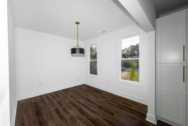 unfurnished dining area with baseboards and dark wood-style floors