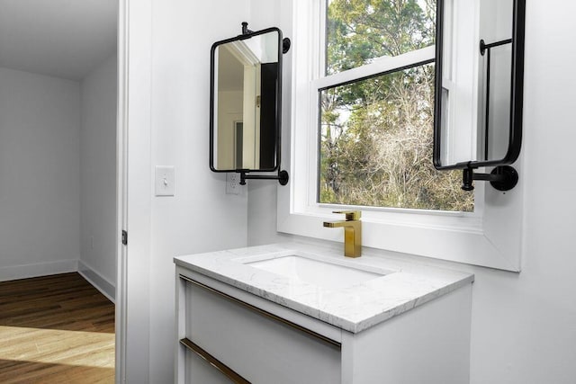 bathroom featuring baseboards, wood finished floors, and vanity