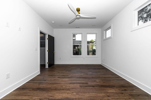 empty room with dark wood-type flooring, visible vents, baseboards, and ceiling fan