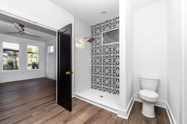 full bath with a tile shower, toilet, and wood finished floors