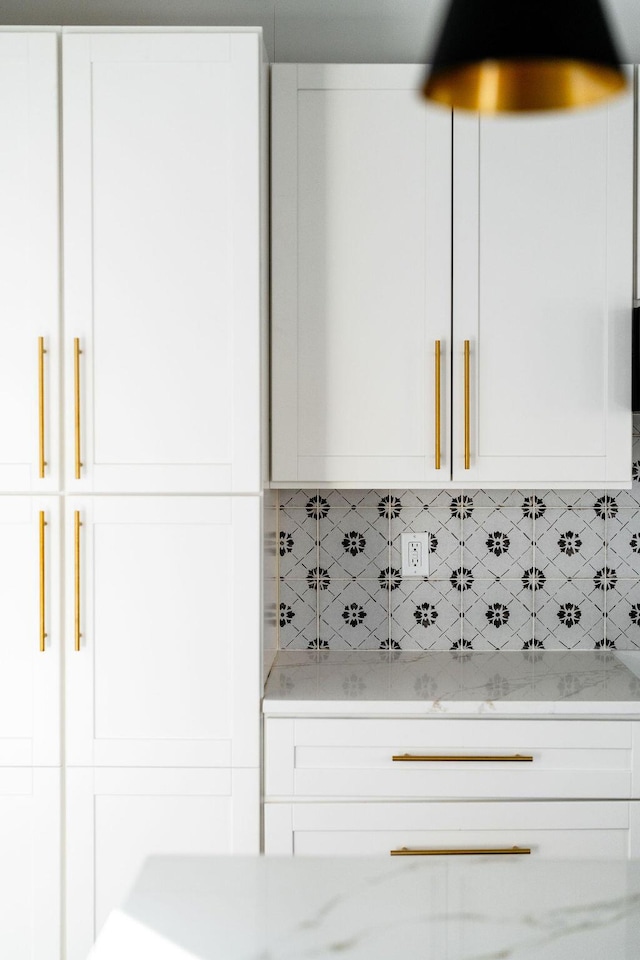 kitchen with light stone countertops, tasteful backsplash, and white cabinets