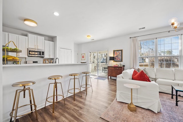 kitchen featuring hardwood / wood-style floors, sink, a breakfast bar area, white cabinets, and kitchen peninsula