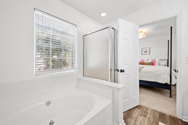 bathroom featuring wood-type flooring and separate shower and tub