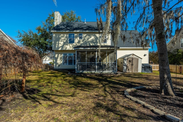 rear view of property with a storage shed, a sunroom, and a lawn