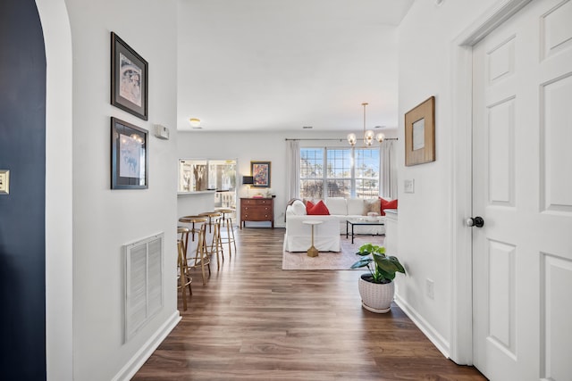 hallway featuring a notable chandelier and dark hardwood / wood-style floors