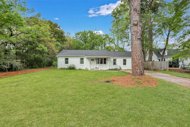 ranch-style house featuring fence and a front lawn