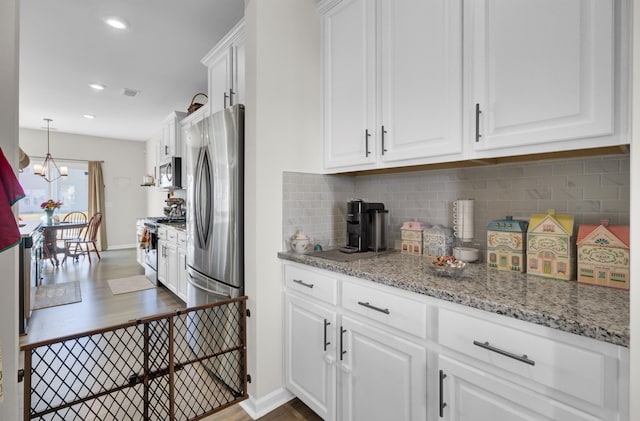 kitchen with white cabinets, decorative light fixtures, dark wood-type flooring, and appliances with stainless steel finishes