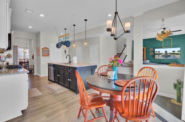 dining room with sink, ceiling fan with notable chandelier, and light wood-type flooring