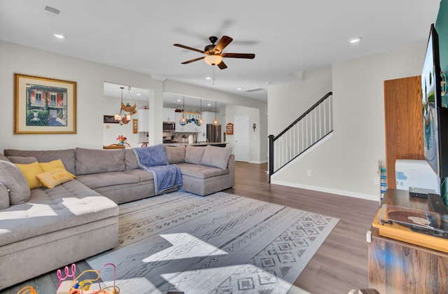 living room with hardwood / wood-style flooring and ceiling fan with notable chandelier