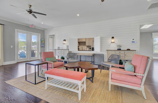 living room featuring ceiling fan, light hardwood / wood-style flooring, wooden walls, and ornamental molding