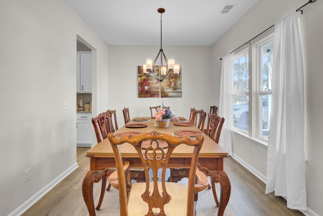 dining space with hardwood / wood-style floors and a chandelier