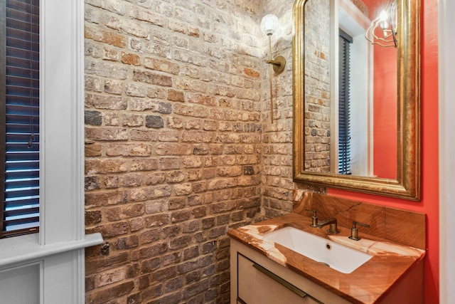 bathroom featuring brick wall and vanity