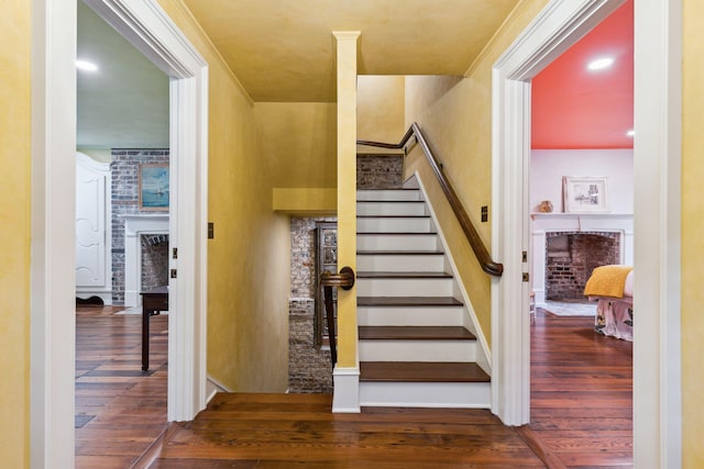 stairs with a fireplace, ornamental molding, wood finished floors, and recessed lighting