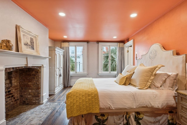 bedroom featuring recessed lighting, dark wood-style flooring, a fireplace, and crown molding