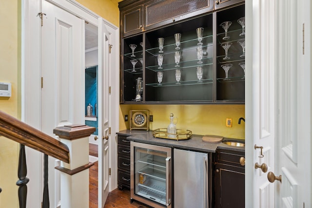 bar with wine cooler, dark wood-type flooring, freestanding refrigerator, bar area, and a sink