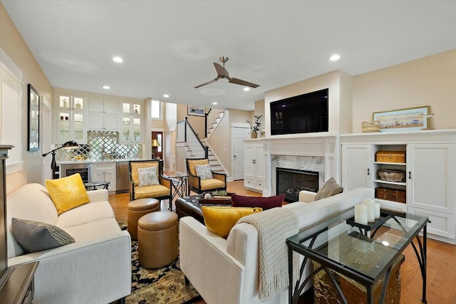 living area featuring a high end fireplace, light wood-type flooring, recessed lighting, and stairs