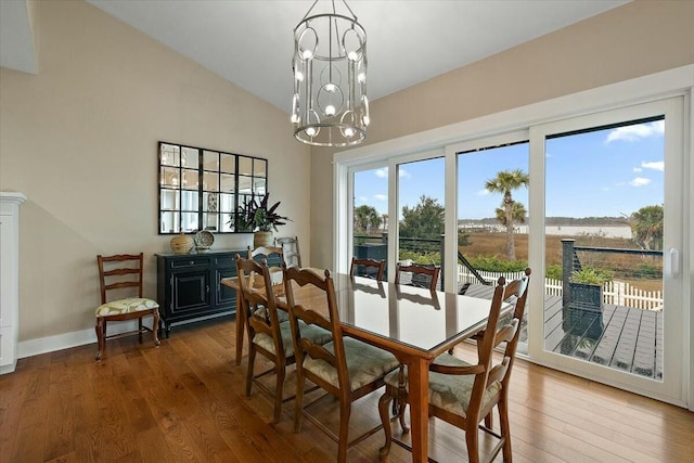 dining area featuring an inviting chandelier, plenty of natural light, vaulted ceiling, and wood finished floors