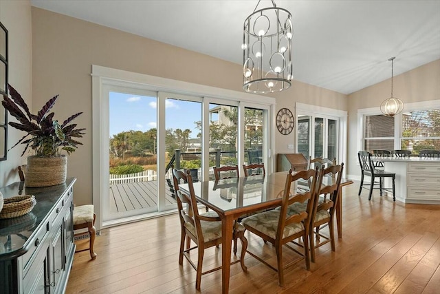 dining space featuring light wood-style floors, lofted ceiling, a chandelier, and a healthy amount of sunlight