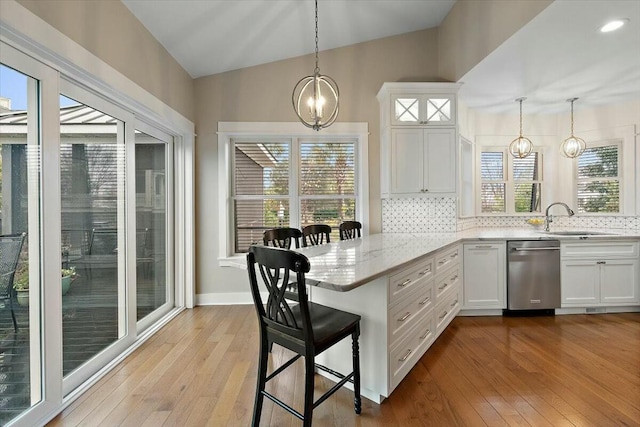 kitchen featuring a peninsula, a kitchen bar, white cabinets, and hanging light fixtures