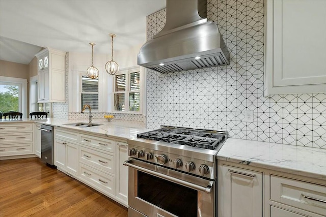 kitchen featuring decorative light fixtures, island exhaust hood, stainless steel appliances, white cabinetry, and a sink