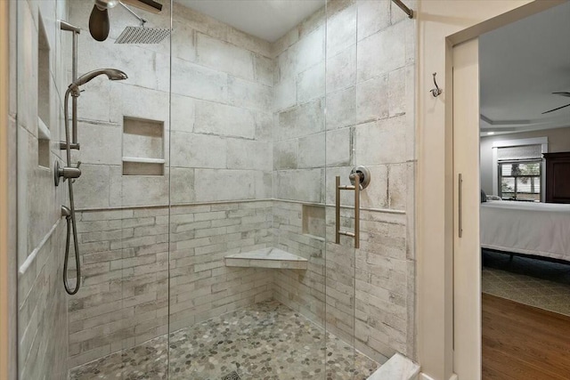 bathroom with a ceiling fan, a shower stall, ensuite bath, and wood finished floors