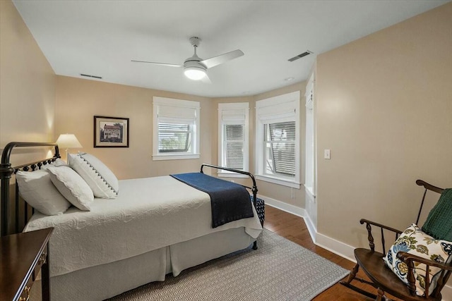 bedroom with baseboards, ceiling fan, visible vents, and wood finished floors