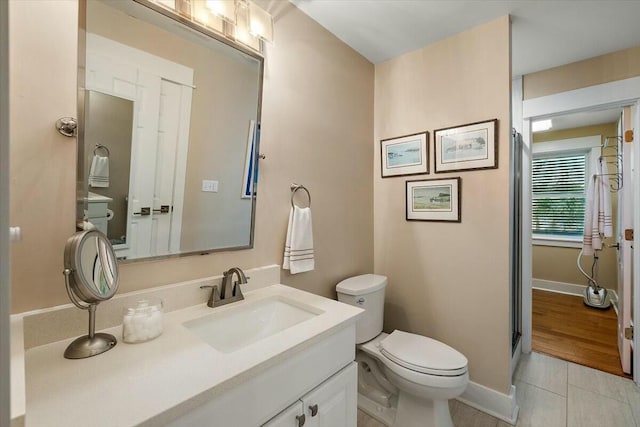 bathroom featuring tile patterned flooring, baseboards, vanity, and toilet